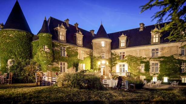 A historic building with ivy-covered walls, a central tower, and a courtyard with outdoor seating. - Hôtel & Spa Château de La Côte - Brantôme (Biras)