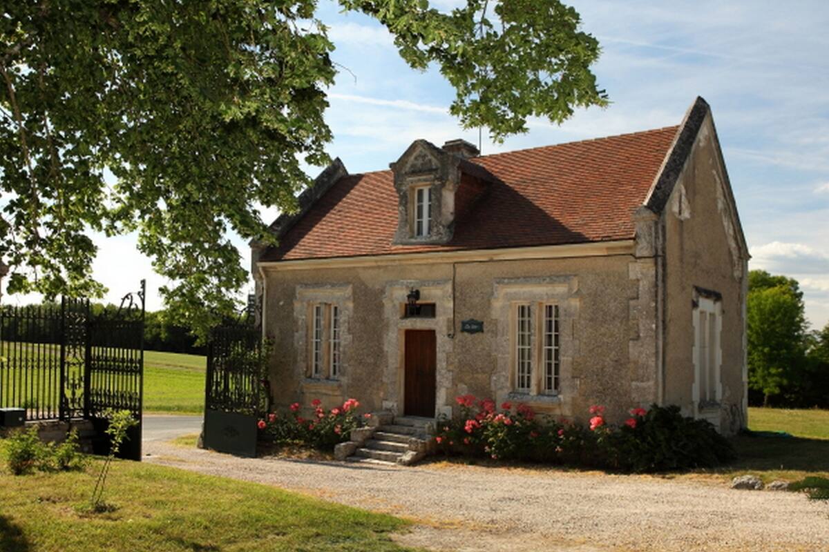 Un bâtiment en pierre avec un toit recouvert de tuiles rouges, une porte en bois et une petite fenêtre.