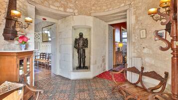 A room with a patterned floor, wooden furniture, a statue, and wall-mounted lamps.