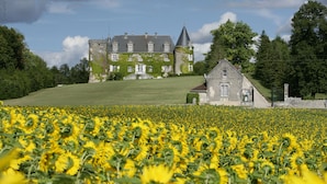 A large estate with a prominent tower, a smaller building, and a sunflower field in the foreground. - Hôtel & Spa Château de La Côte - Brantôme (Biras)