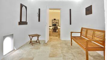 A hallway with a wooden bench, a small table, and a mirror on the wall.
