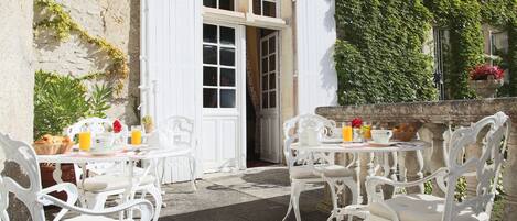 An outdoor dining area with white furniture and a stone wall.