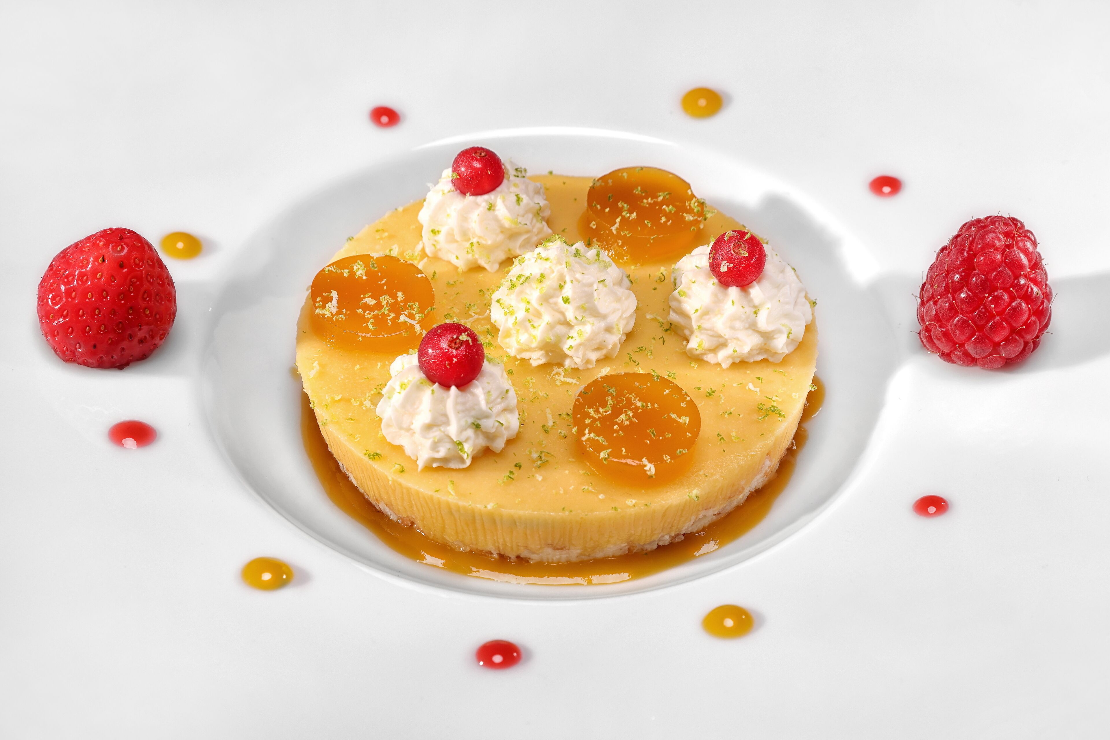 Un plato de postre con un pastel cremoso, fruta y crema batida.