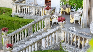 A stone staircase with balustrades leading to a terrace with outdoor seating and potted plants. - Hôtel & Spa Château de La Côte - Brantôme (Biras)
