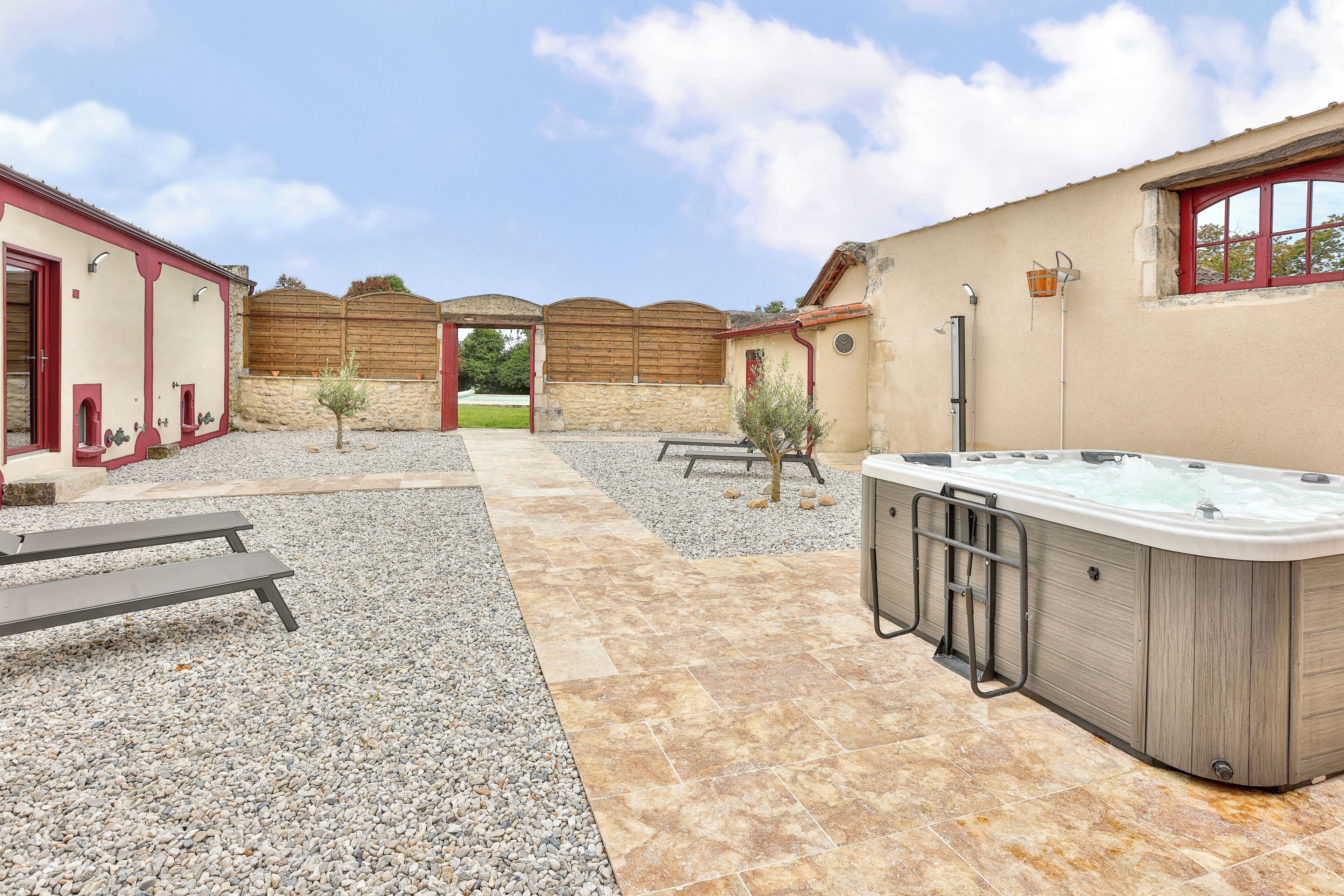A spa area with a hot tub, stone walls, and a gravel path.