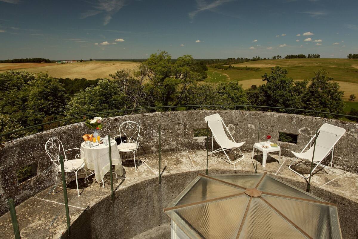 Une terrasse dotée de chaises et de tables en métal blanc, donnant sur un terrain de golf.