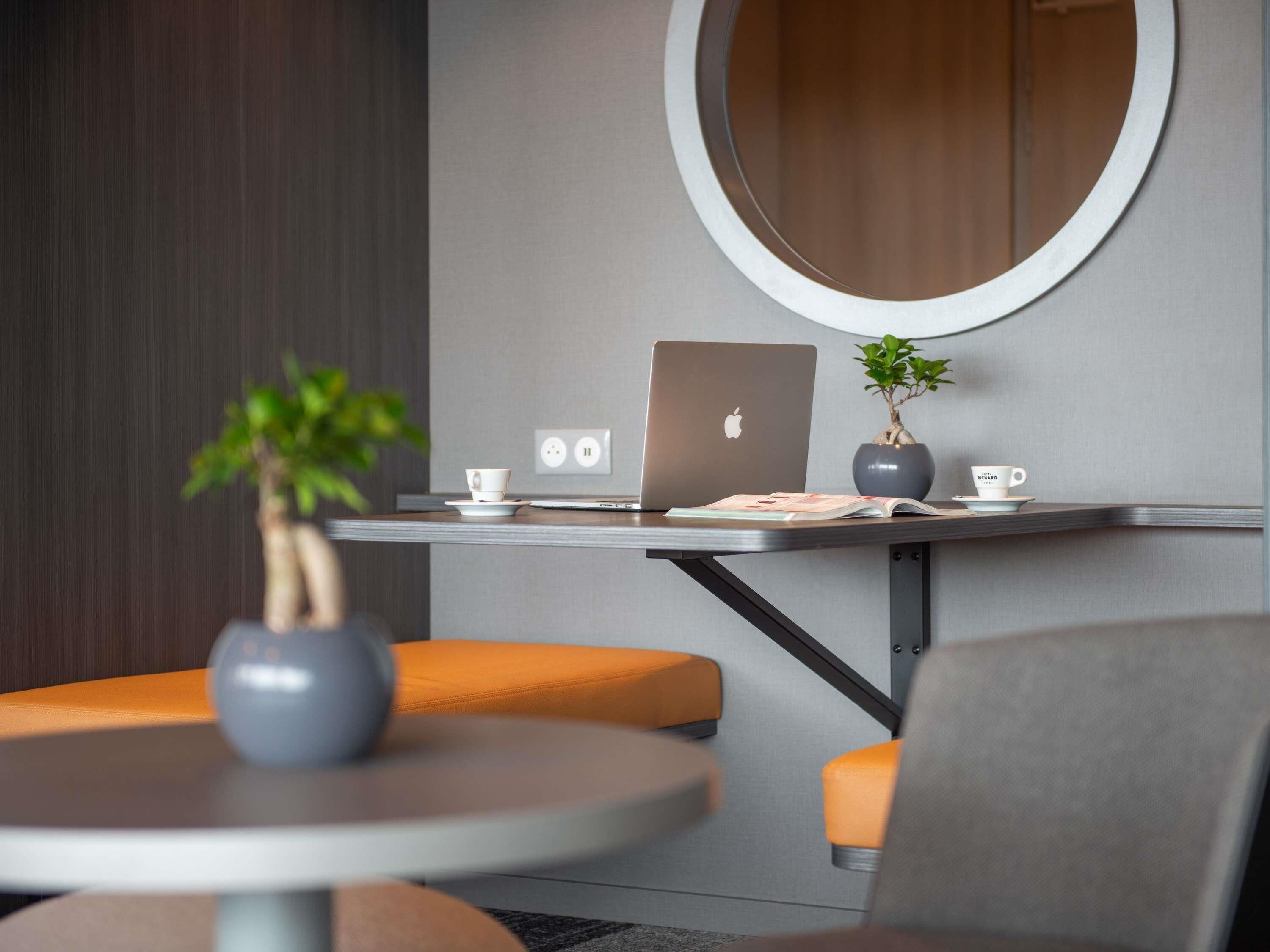 A modern workspace with a laptop, a potted plant, and a cup on a table.