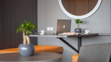 A modern workspace with a laptop, a potted plant, and a cup on a table.