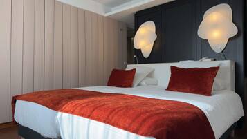 A modern bedroom with a large bed, white bedding, and two wall-mounted lamps.