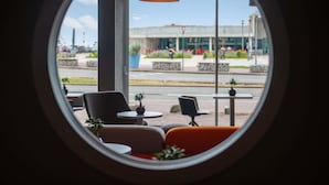 A circular window view of a modern interior with seating and a hanging light fixture. - Mercure Dieppe La Présidence (Dieppe)