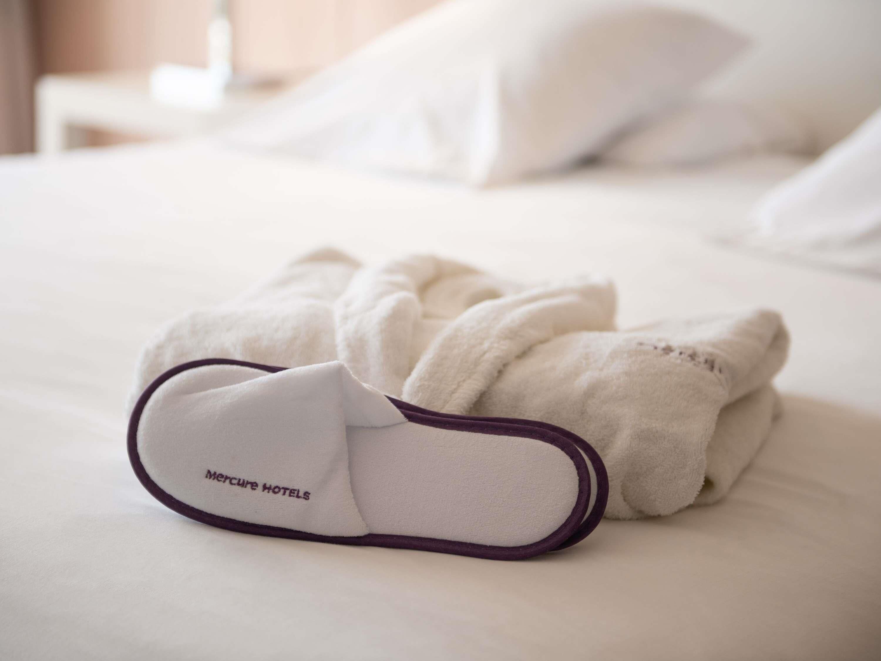 A neatly made bed with white linens and a purple edge on the foot of the bed.