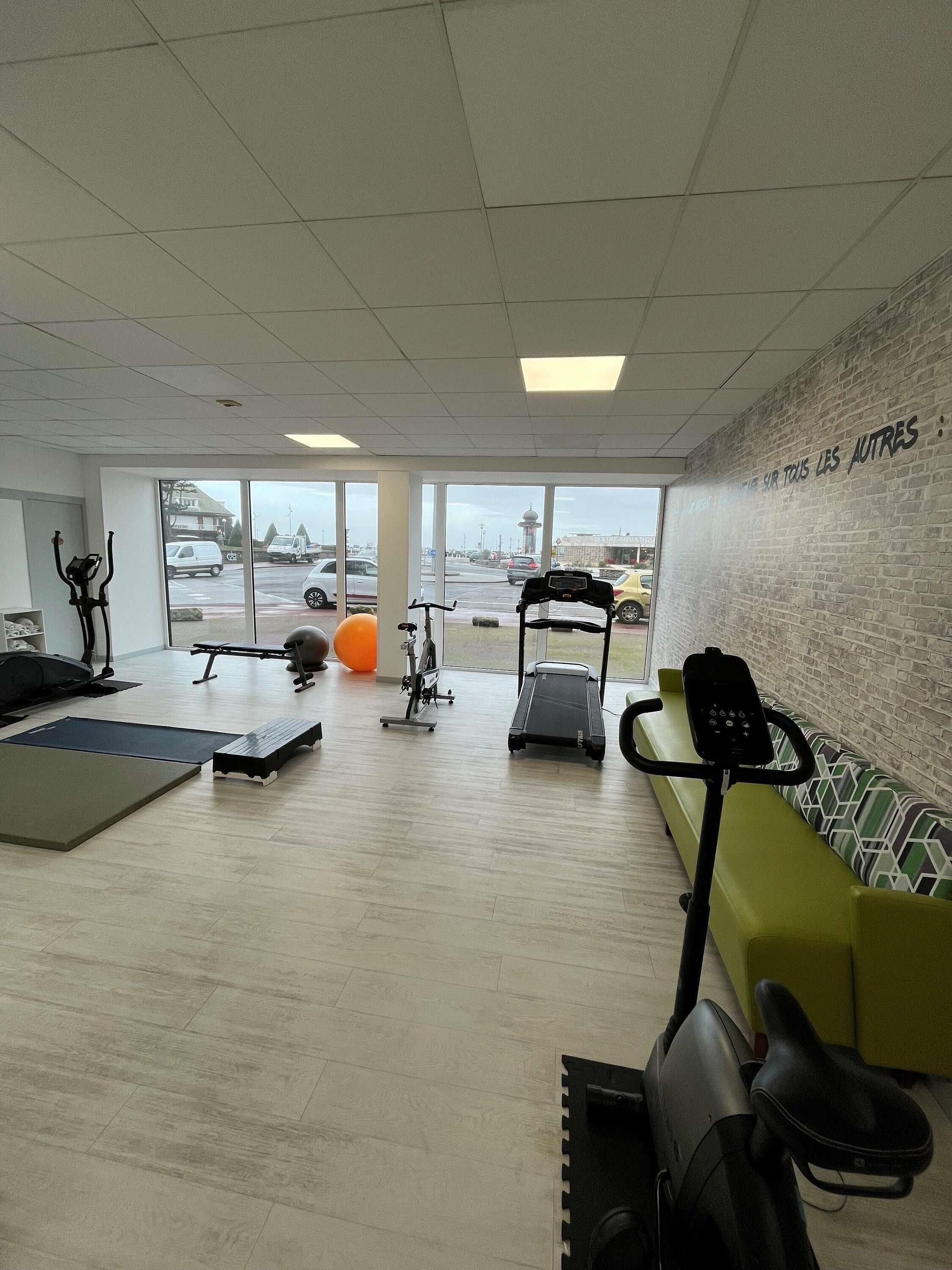 Une salle de sport équipée de matériel d’exercice, d’un tapis de course et d’un mur avec du texte.
