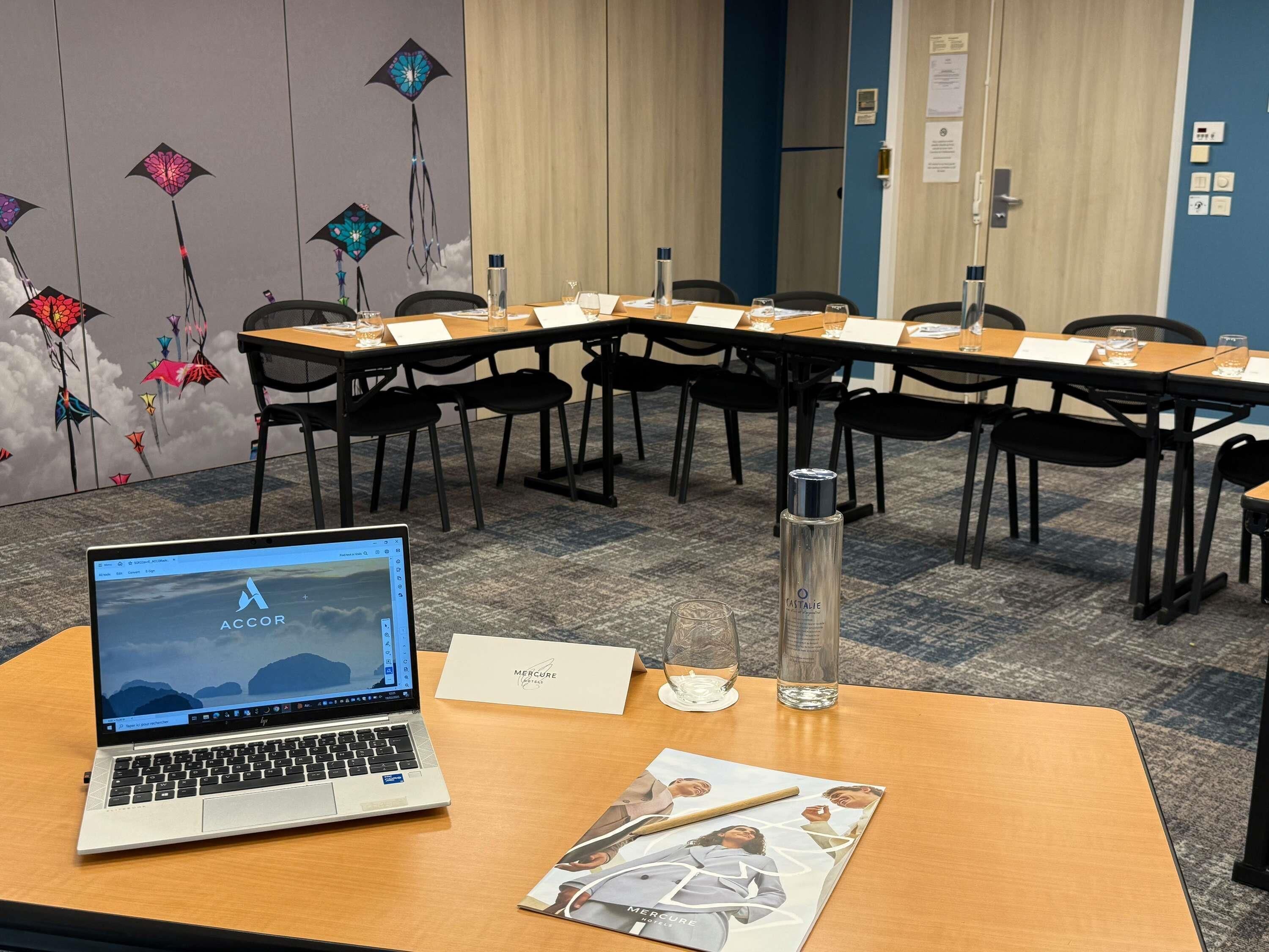 A conference room with a laptop, documents, and a water bottle on a table.