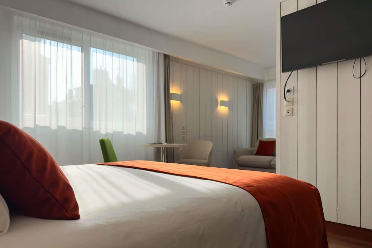 Una habitación de hotel con cama, escritorio, silla y televisión.