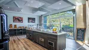 Una cocina moderna con una isla central, suelo de madera y amplios ventanales con vistas a la vegetación.
