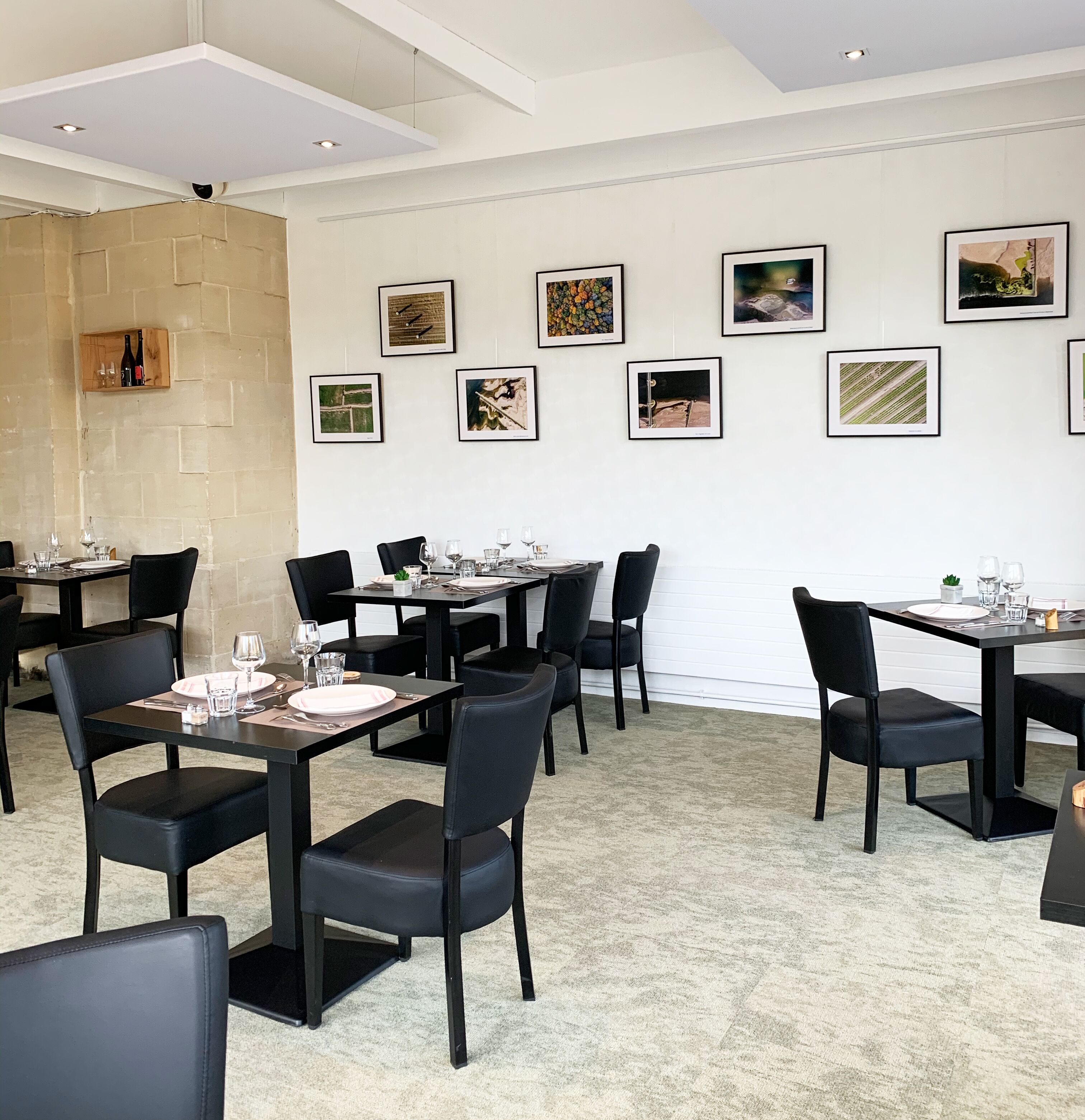Un espace de restauration moderne, doté de plusieurs tables et chaises, d’un mur d’accent en pierre et d’œuvres d’art encadrées qui ornent les murs.