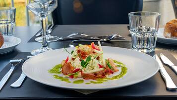 A plate of food with a green sauce, accompanied by a glass of water and a glass of wine on a table.