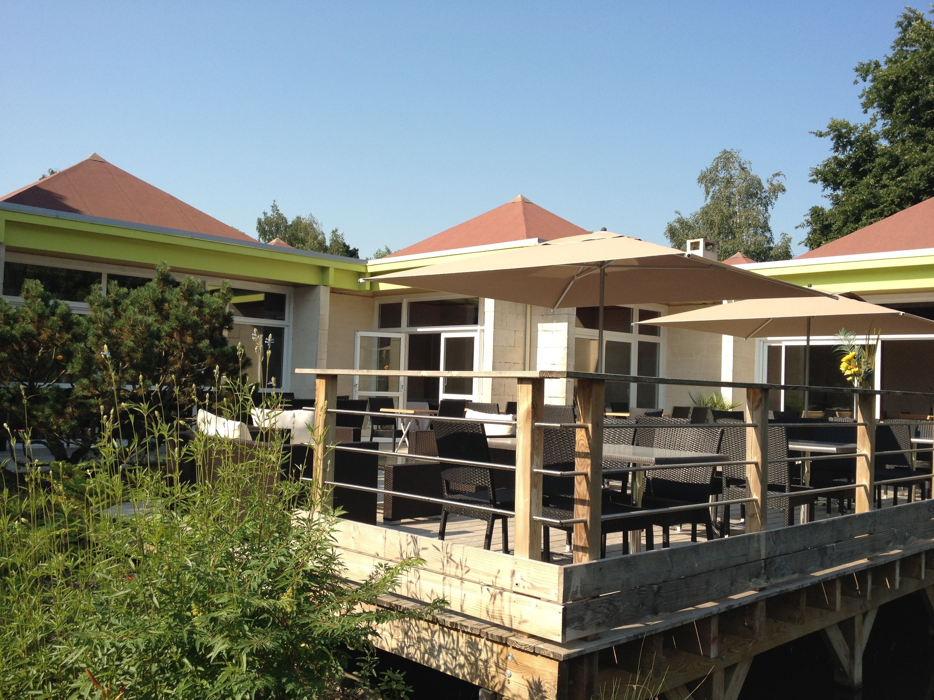 A wooden deck with outdoor seating and umbrellas, overlooking a body of water.