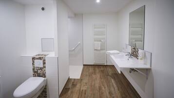 A modern bathroom with a toilet, bidet, and a sink with a mirror.