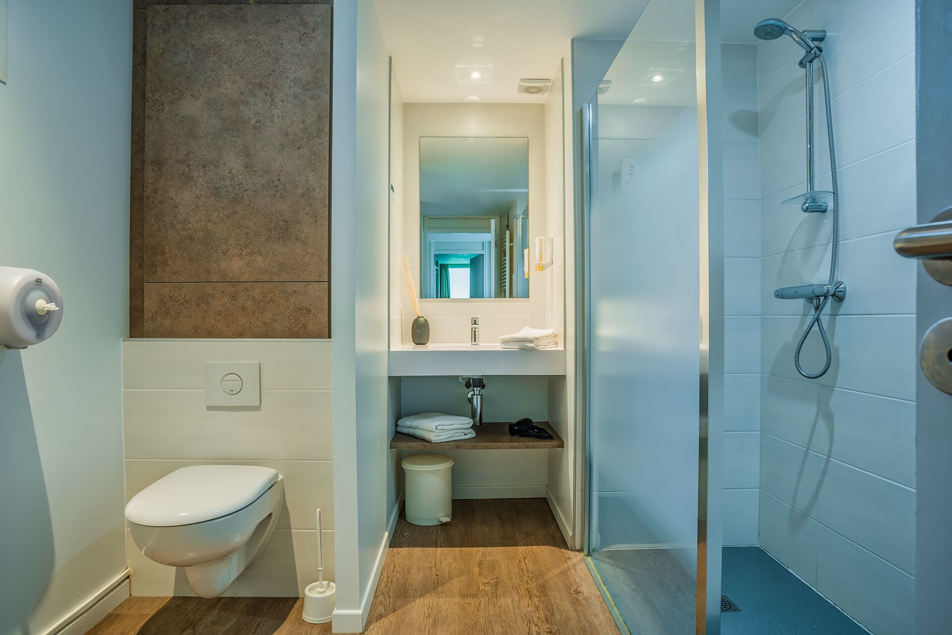 A modern bathroom with a toilet, sink, and shower.