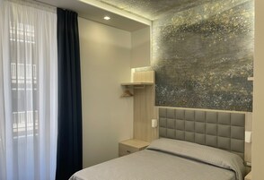 Una moderna camera d'albergo con un letto, comodini, una lampada a sospensione e una decorazione a parete.