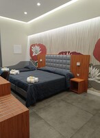 Una camera d'albergo moderna con un letto grande, una scrivania in legno e una parete decorata con un murale floreale.