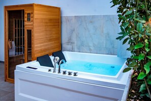 A modern spa room with a large white bathtub, wooden sauna, and marble walls. - Villa Elisio Hotels & Spa (Naples)