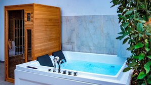 A modern spa room with a large white bathtub, wooden sauna, and marble walls. - Villa Elisio Hotels & Spa (Naples)