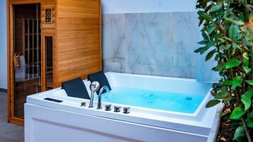 Um spa moderno com uma banheira grande e branca, sauna de madeira e paredes de mármore.