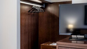 A walk-in closet with wooden paneling, a hanging rack, and a flat-screen TV on a wooden cabinet. - Hotel Stadio (Piacenza)
