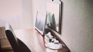 A wooden desk with a computer monitor, a keyboard, and a plate with condiments. - Hotel Aurelia (Frankfurt)