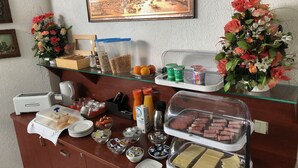 A buffet setup with various food items, a coffee machine, and decorative flowers. - Hotel Aurelia (Frankfurt)