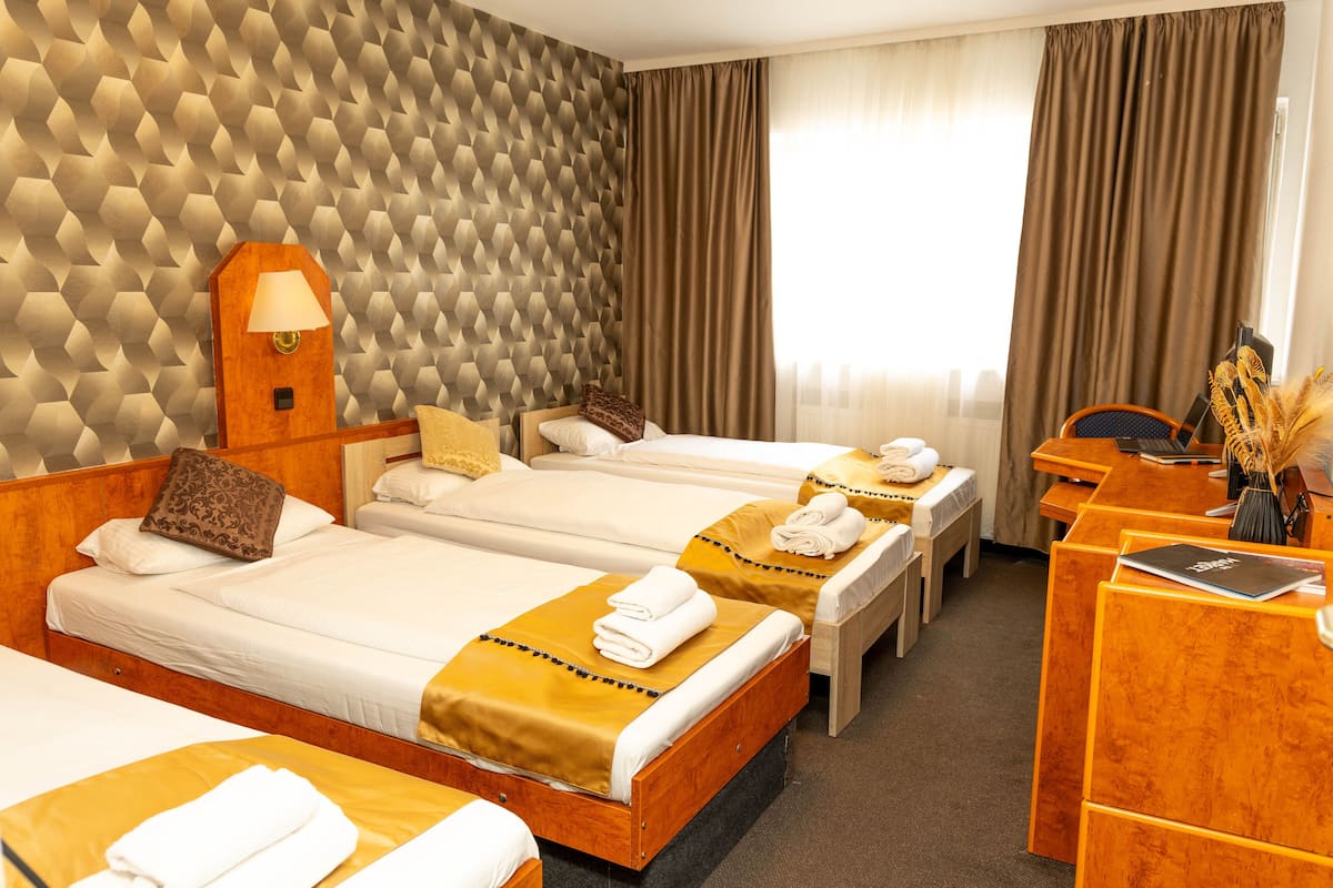 A hotel room with two beds, a desk, and a lamp.