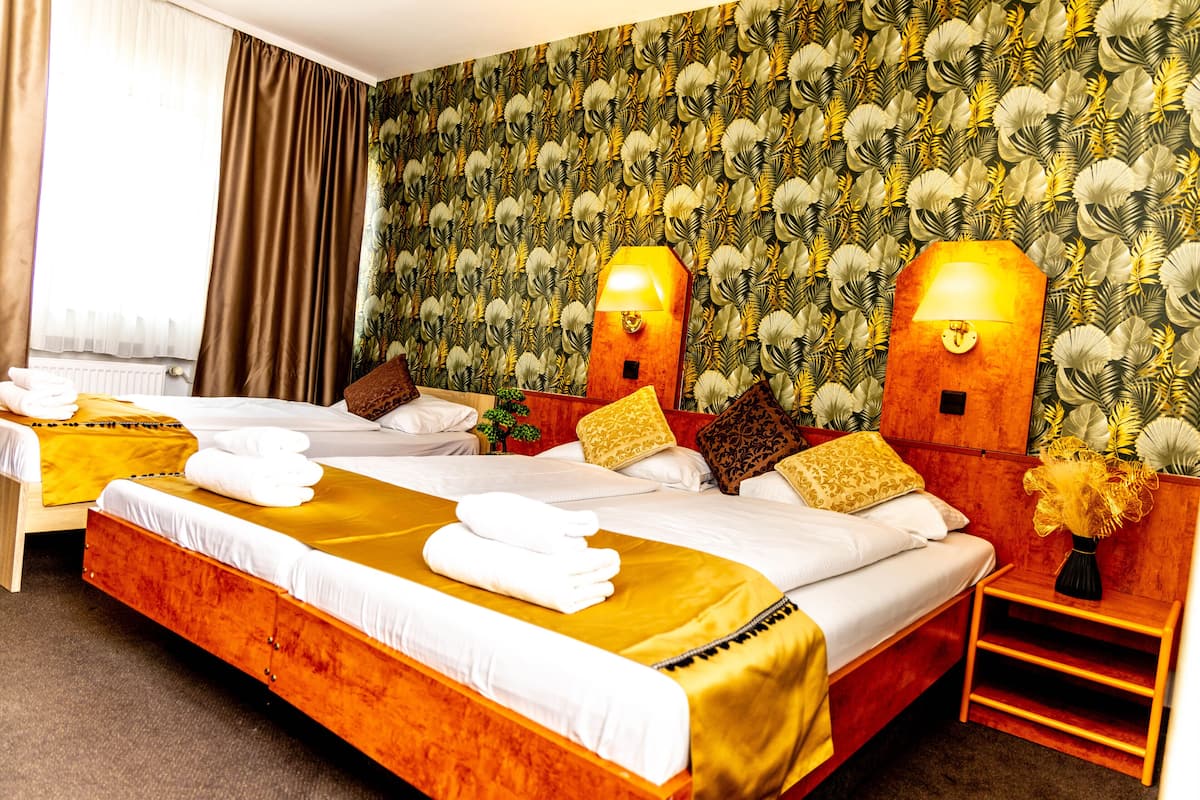 A hotel room with a large bed, two bedside tables, a nightstand, and a wall with a leafy pattern.
