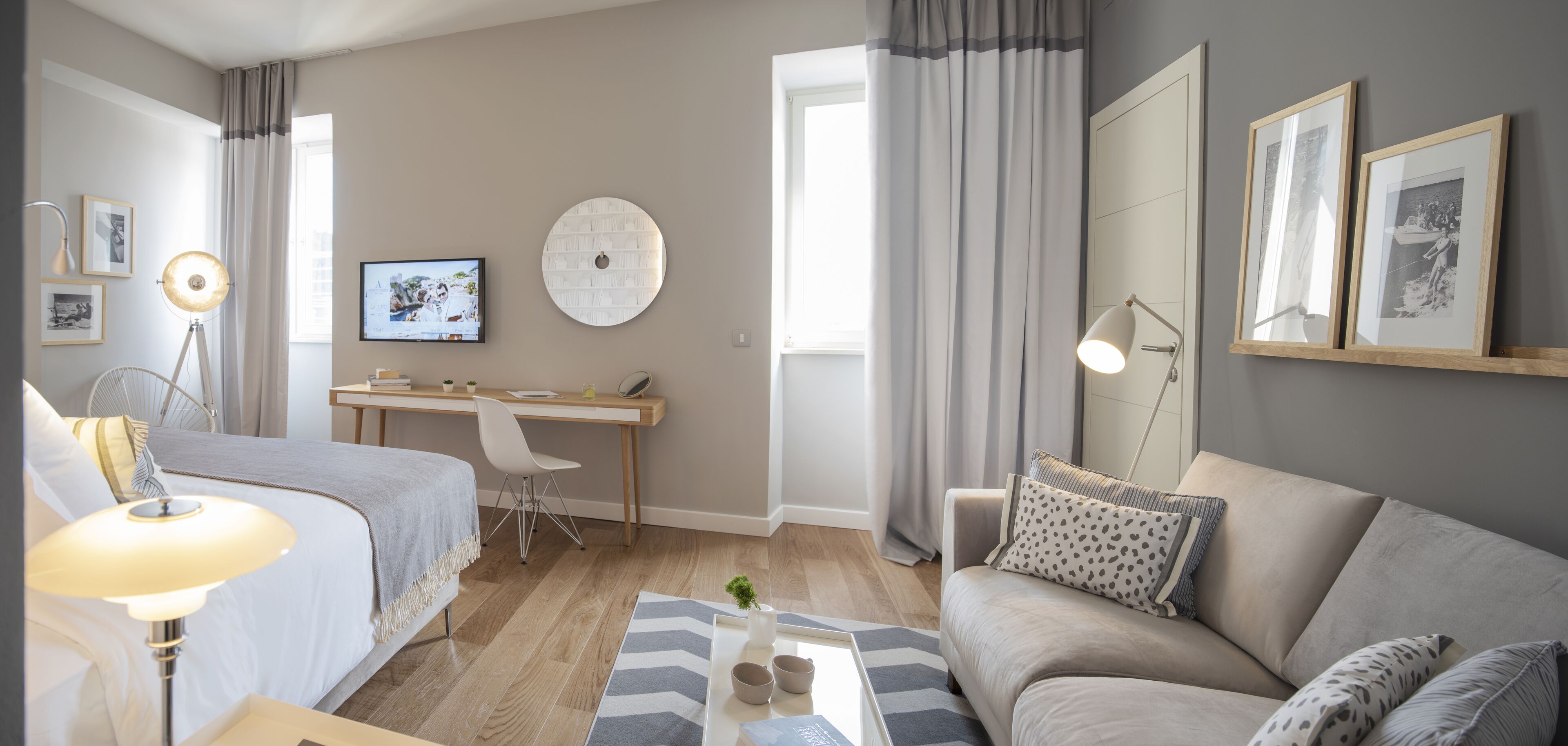A modern bedroom with a bed, bedside table, lamp, and a desk with a chair.