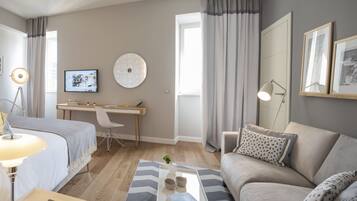 A modern bedroom with a bed, bedside table, lamp, and a desk with a chair.