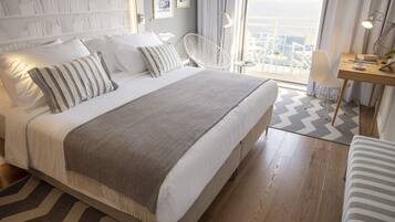 A modern hotel room with a large bed, a desk, and a view of the city.
