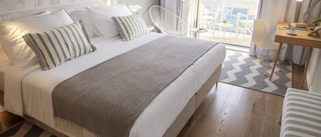 A modern hotel room with a large bed, a desk, and a view of the city.
