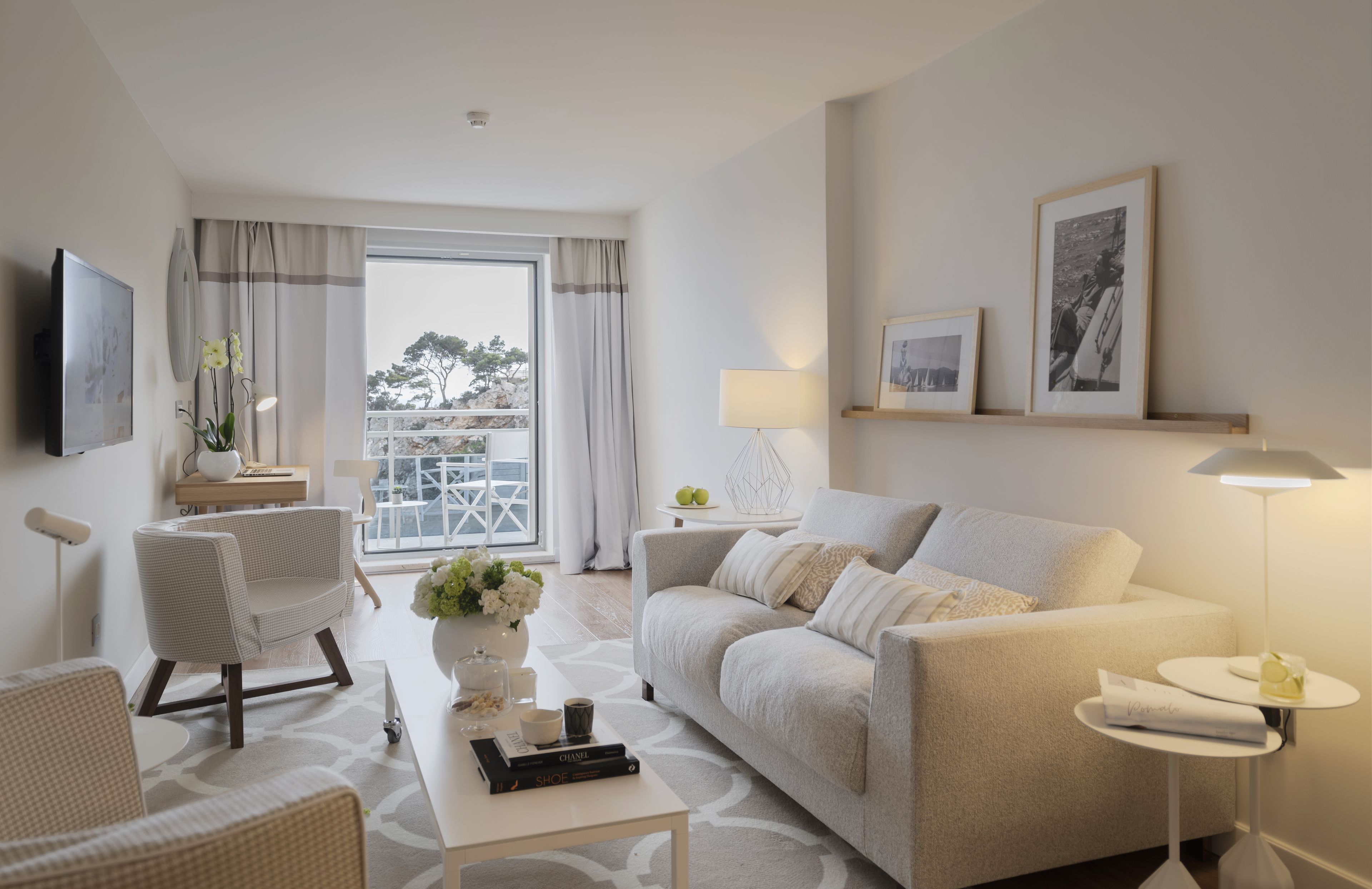 A modern living room with a sofa, armchairs, a coffee table, and a TV mounted on the wall.