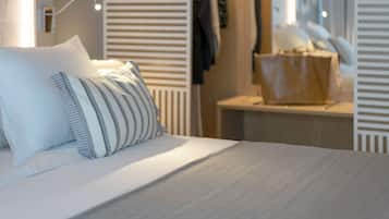 A modern bedroom with a bed, pillows, a nightstand, and a wardrobe with a mirror.