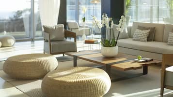 A modern living room with a sofa, two armchairs, a coffee table, and a large window with a view.