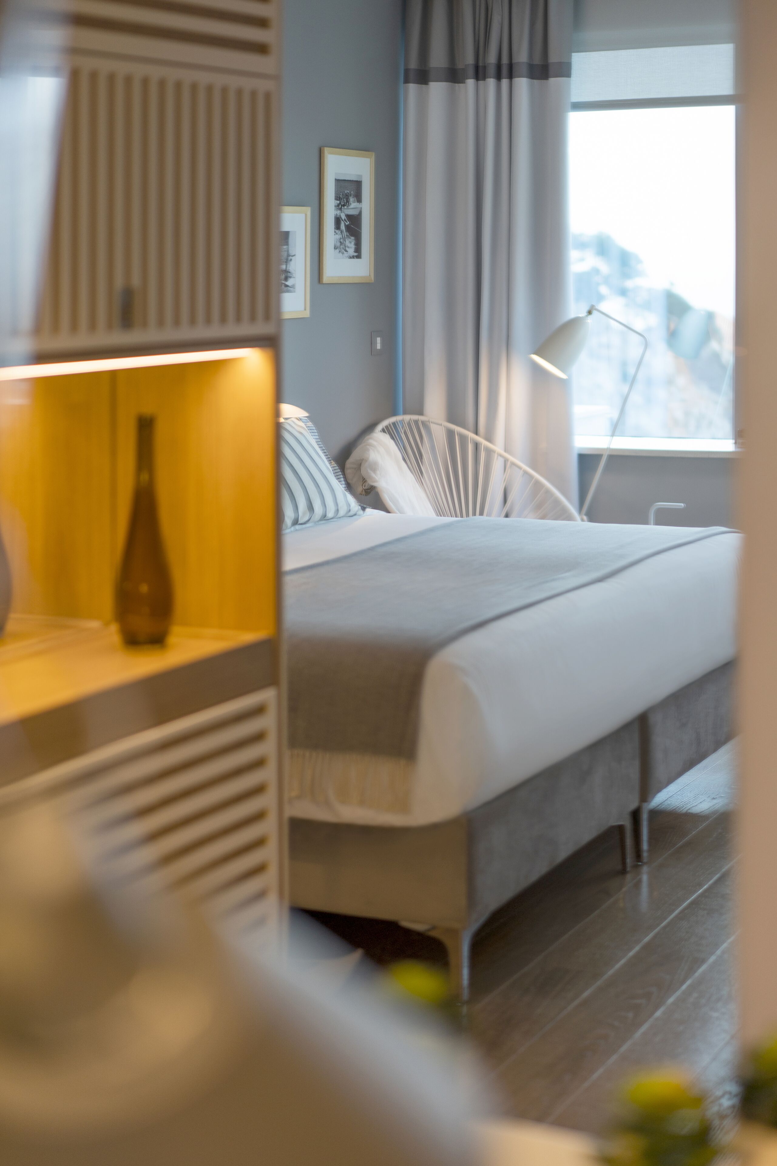 Une chambre moderne avec un lit, une lampe de chevet et une vue sur les montagnes par la fenêtre.
