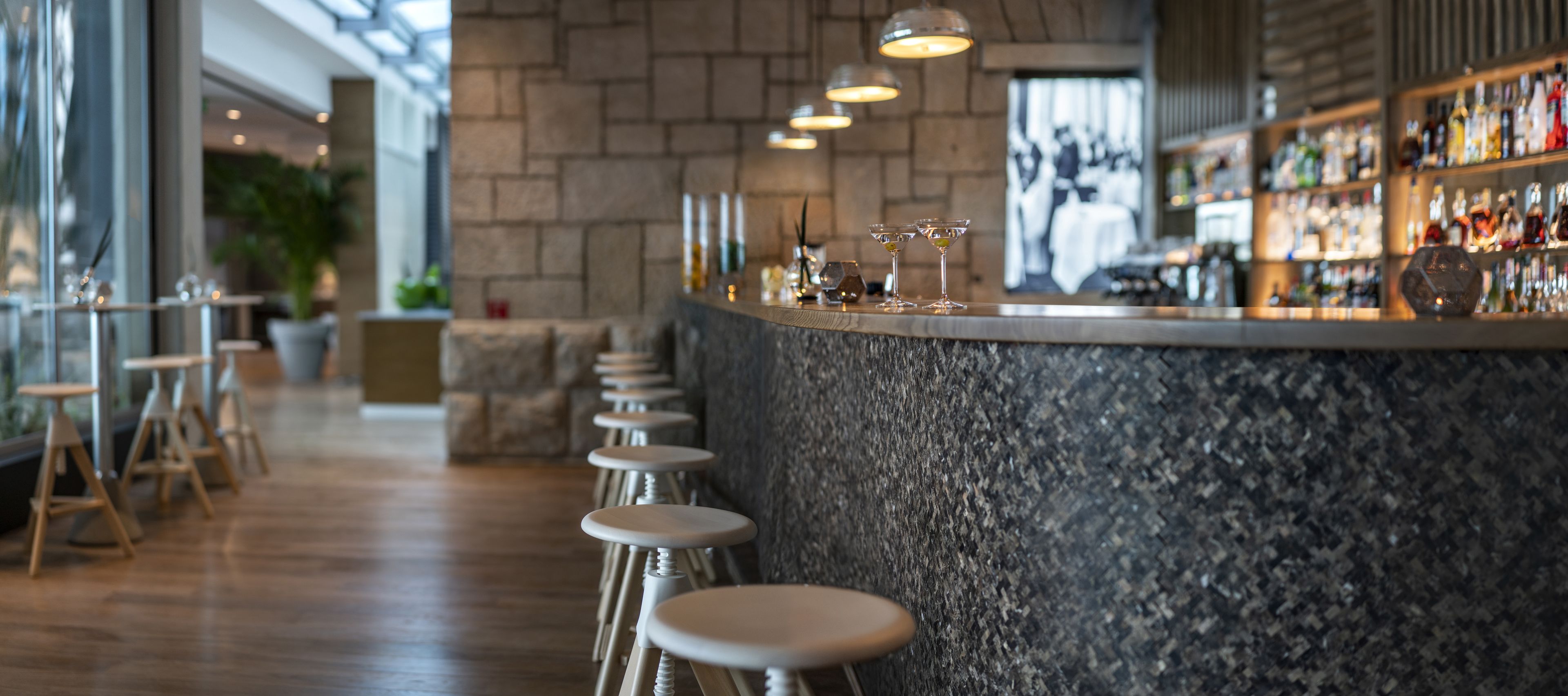 Zona de bar con mostrador de piedra, taburetes y una barra bien surtida.