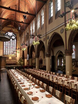 A large hall with long tables set for dining, arched ceilings, and a Christmas tree. - Monasterium PoortAckere (Ghent)