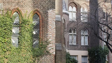 Un edificio histórico con ventanas cubiertas de hiedra, una bicicleta y un camino adoquinado.