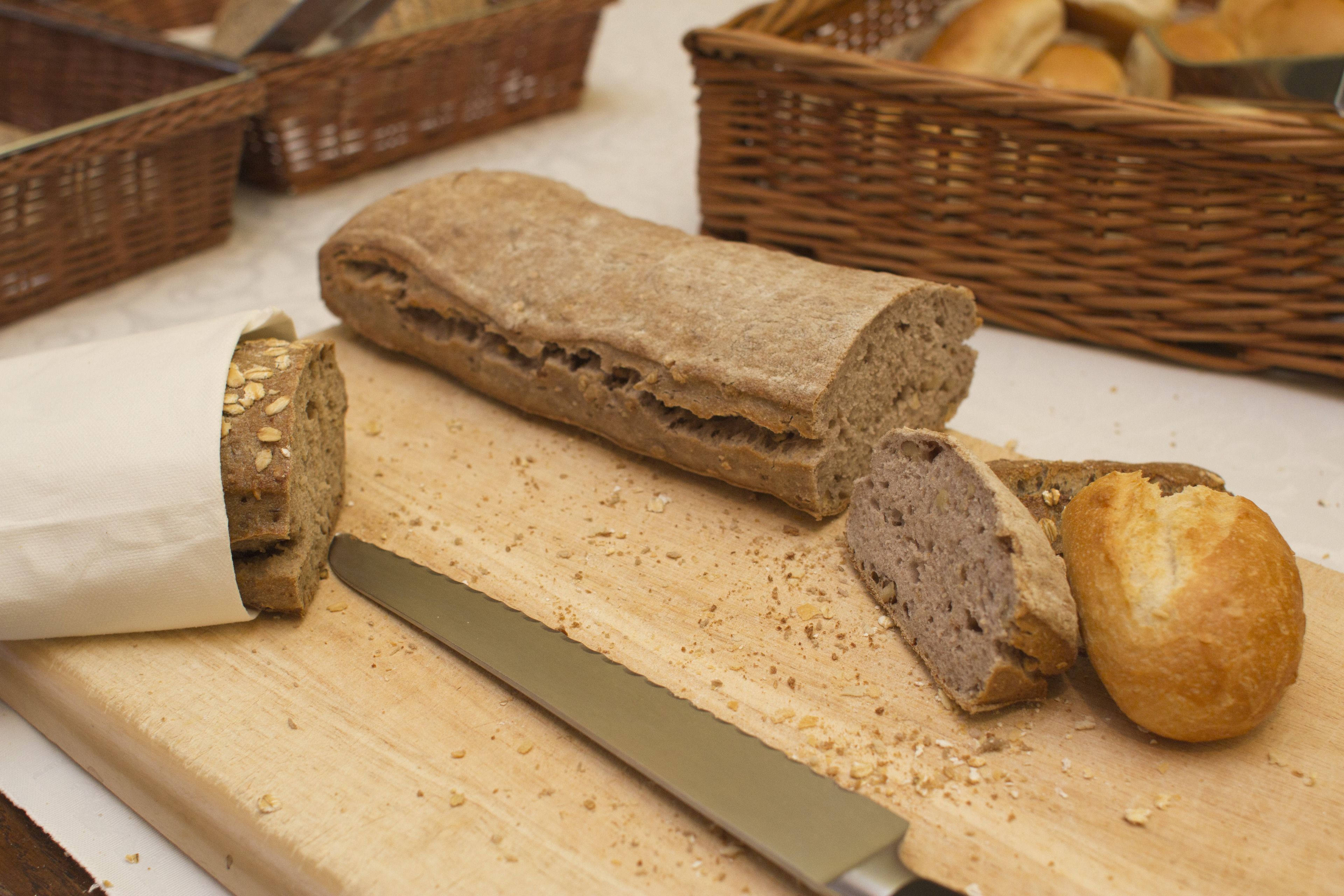 Een brood op een snijplank met een mes, omringd door rieten manden.