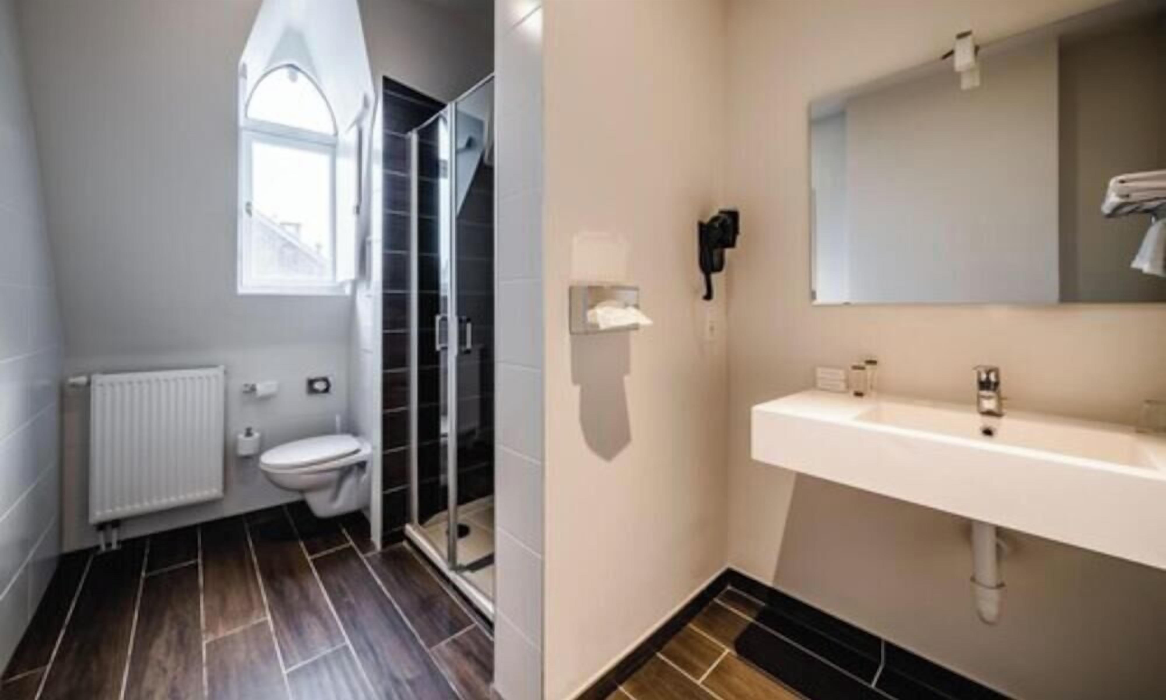 A bathroom with a toilet, shower, and sink.