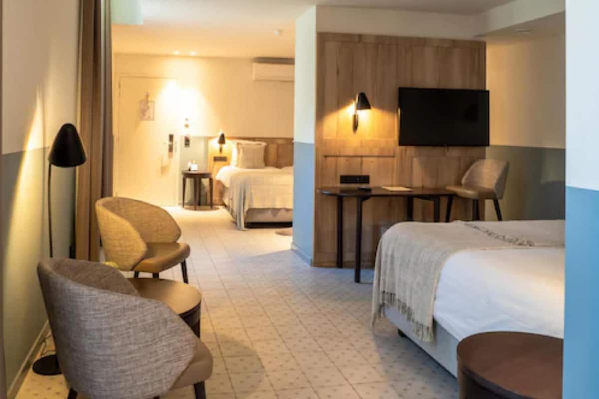 A hotel room with a bed, a desk, a chair, and a television.