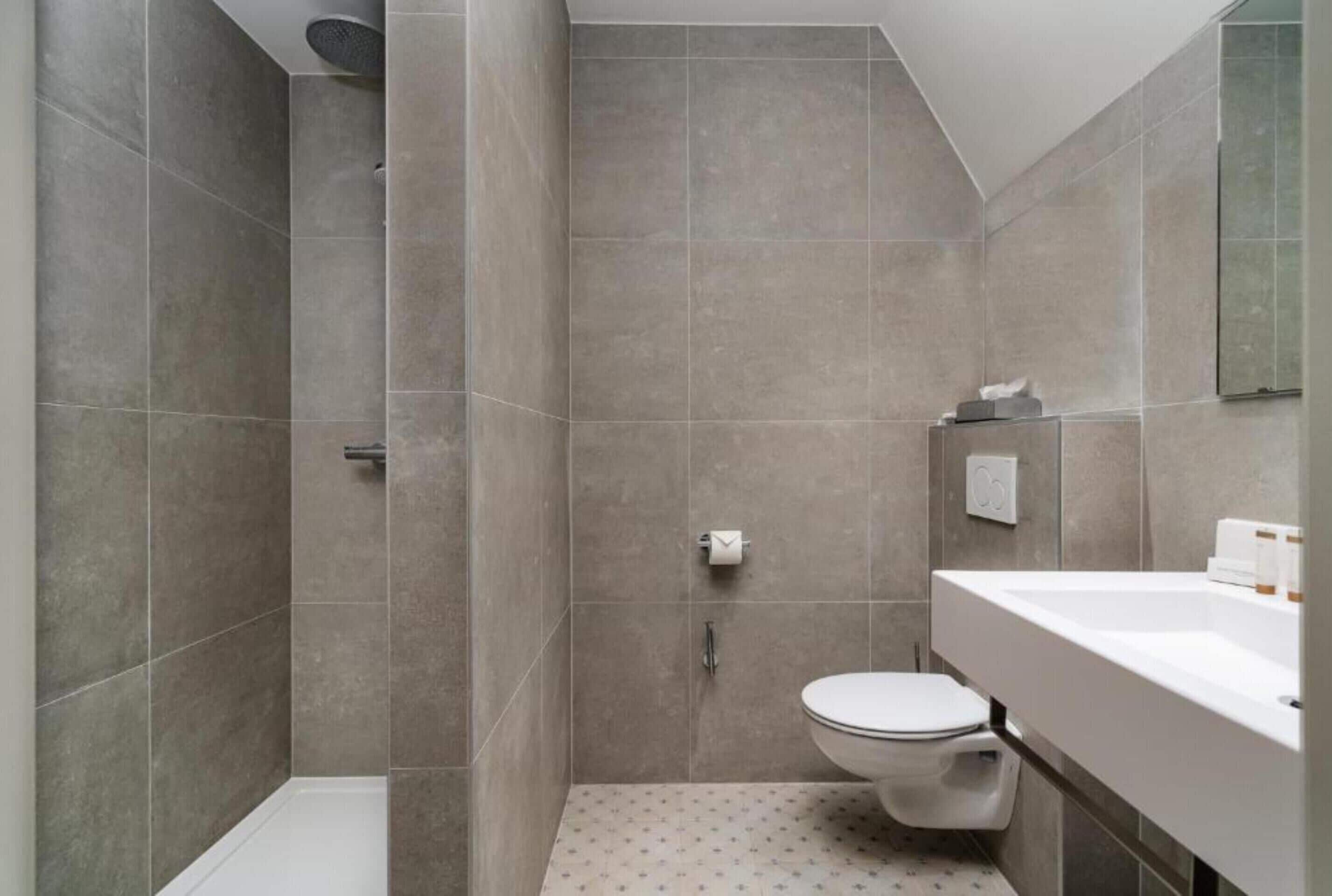 A modern bathroom with a shower, toilet, and sink.