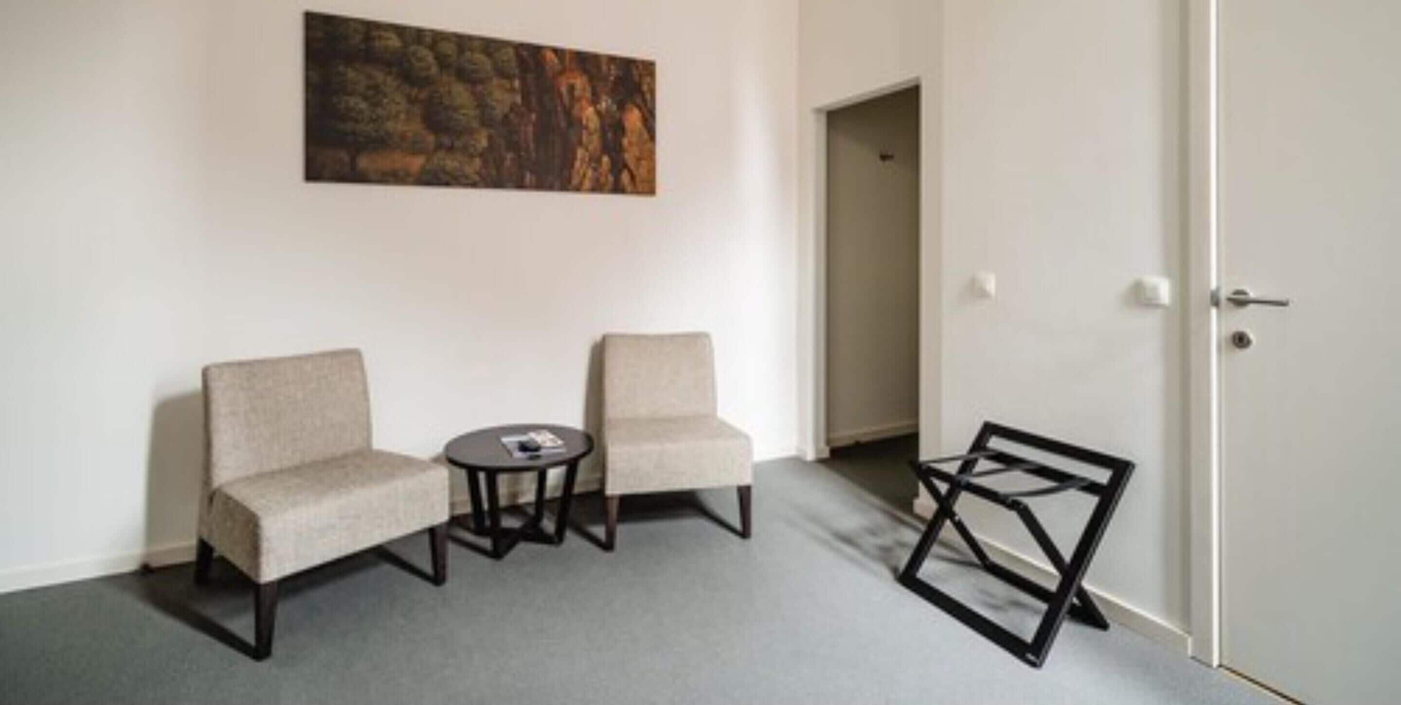 A room with two armchairs, a small round table, and a door.